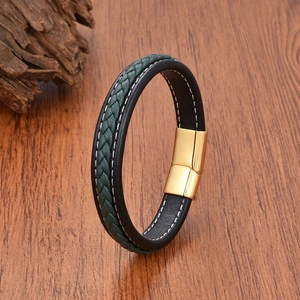 Detail of woven black and green leather bracelet with gold magnetic clasp on wood
