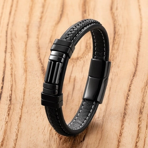 Detail van gevlochten zwarte lederen armband met roestvrijstalen magneetsluiting en stiksels