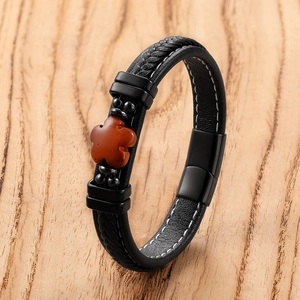 Detail of black braided leather bracelet with red stone flower and magnetic metal clasp