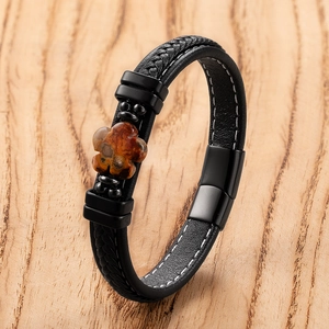Black woven leather bracelet with flower stone charm and magnetic clasp on wood surface