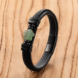Detail of woven leather bracelet with green clover bead and magnetic clasp closure