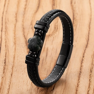 Detailed macro view of woven black leather bracelet featuring a green clover stone inlay