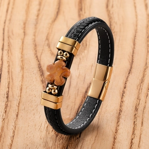 Detail of leather woven bracelet featuring a clover stone and gold magnetic clasp