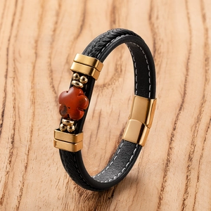 Macro view of braided leather bracelet with red stone clover and gold magnetic clasp