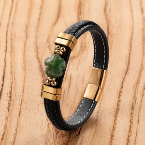 Detail of black woven leather bracelet with green clover stone and gold magnetic clasp