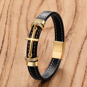 Dettaglio del bracciale in pelle nera intrecciata con croce dorata e chiusura magnetica