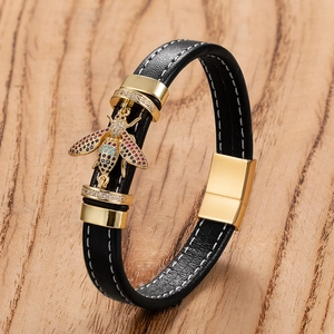 Detail of black woven leather bracelet with golden bee charm and color stones
