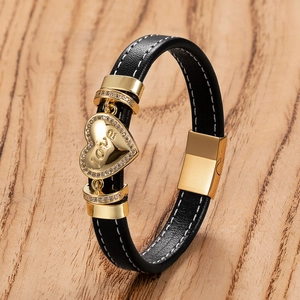 Detail eines schwarzen Lederarmbands mit goldenem Herzanhänger und funkelnden Kristallen