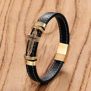 Close-up of black leather bracelet with gold cross pendant and magnetic buckle on wood