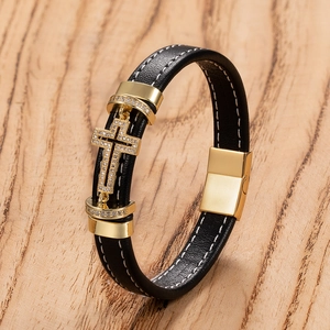 Macro view of black leather bracelet with golden cross and white stitching detail