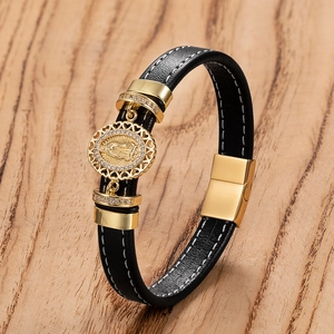 Détail du bracelet en cuir noir avec pendentif religieux doré et fermoir magnétique chic
