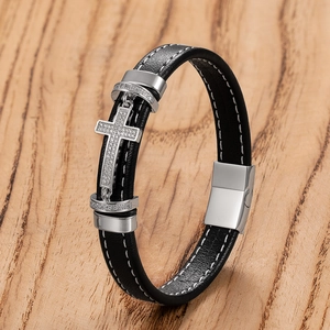 Detail of black leather bracelet with crystal-encrusted silver cross and magnetic clasp