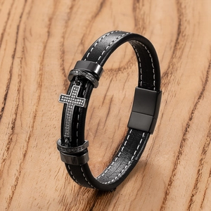 Macro shot of a men's black leather bracelet with a crystal cross and magnetic clasp
