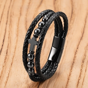 Detailed macro view of black braided leather multi-layer bracelet with metallic cross