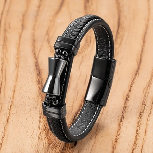 Detail of black braided leather bracelet with central metal bowtie clasp on wood surface