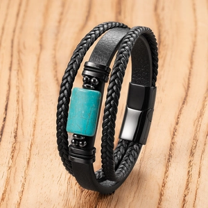 Detail of multi-layer leather bracelet with turquoise bead and magnetic clasp on wood