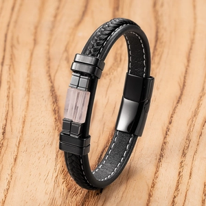 Detail van herenarmband van zwart gevlochten leer met magneetsluiting en roze steen