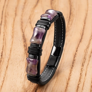 Dettaglio di un bracciale in pelle nera con tre pietre di ametista viola e chiusura in metallo