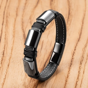 Dettaglio di un bracciale da uomo in pelle nera con cuciture bianche e chiusura lucida