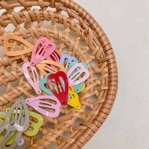 Close-up of colorful heart-shaped metal hair clips in a woven basket display