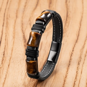 Dettaglio di pietre occhio di tigre marroni e cinturino in pelle nera con chiusura magnetica
