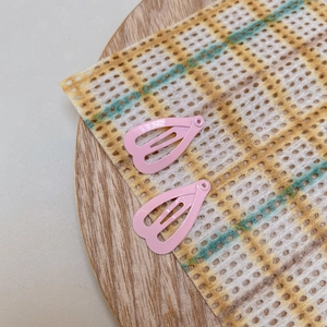 Close-up of pink heart-shaped metal hair clips with a matte lacquer finish for pets and dolls