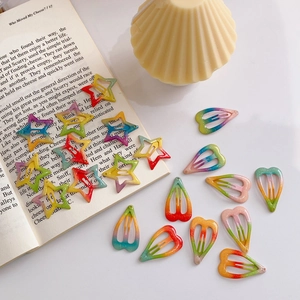 Detailed shot of rainbow gradient glitter star and heart hair clips on a book page