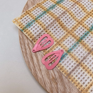 Close-up of two pink heart-shaped mini metal BB clips on a wooden decorative tray