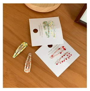 Détail de quatre barrettes BB en métal avec motifs de fruits sur bois naturel