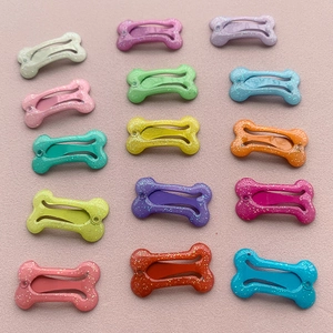 Dettaglio di 15 fermagli colorati a forma di osso con finitura glitterata per bambini