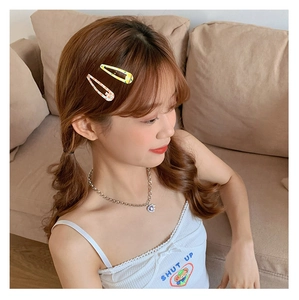 Gros plan de barrettes à cheveux citron et pois avec un collier pendentif violet