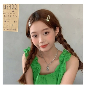 Détail d'un collier avec pendentif ours 3D argenté porté par un mannequin stylé