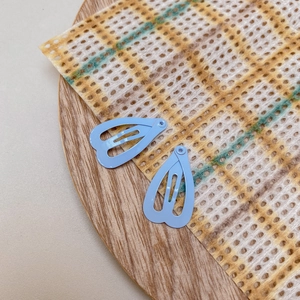 Close-up of light blue heart-shaped matte hair clips on a yellow lace background