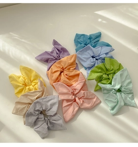 Detailed top view of nine macaron colored fabric scrunchies with bunny ear bow designs