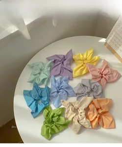 Set of 9 candy-colored fabric scrunchies with bow details on a white table