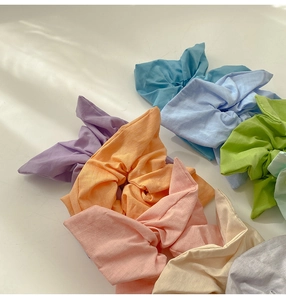 Detailed view of colorful cotton scrunchies with bow design on a white table