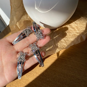Close-up of four silver butterfly hair clips with sparkling rhinestones held in hand