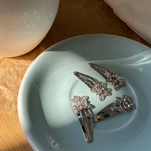 Detail of four silver butterfly hair clips with sparkling rhinestones in a blue tray