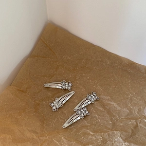 Detail view of 4 silver rhinestone butterfly hair clips on brown kraft paper background