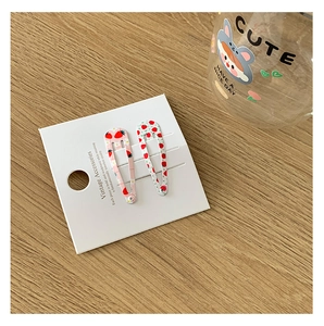 Détail de pinces à cheveux fraise de 5 cm avec motifs à carreaux sur carton