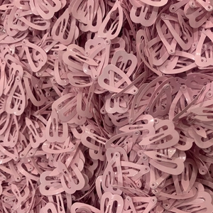 Detailed macro view of heart-shaped mini snap clips in pink painted metal bulk