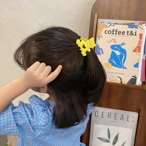Vue détaillée d'une pince à cheveux fleur jaune mat portée par une fille aux cheveux foncés