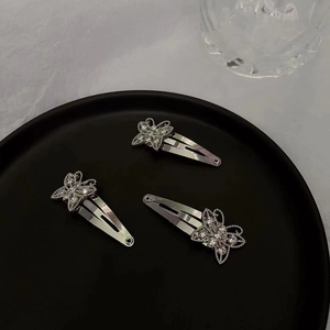 Detailed view of three silver butterfly hair clips with sparkling rhinestones in a tray