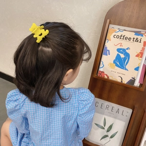 Gros plan d'une pince à cheveux ours jaune pour filles sur une petite queue de cheval