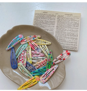 Close-up of colorful floral fruit pattern BB hair clips in a ceramic display tray