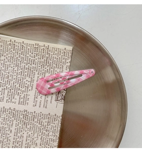 Detailed view of pink and white checkered snap hair clip on a vintage background