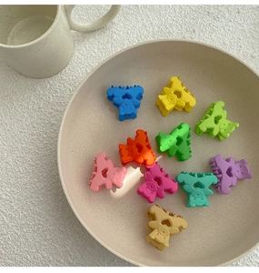 Détail de dix mini pinces à cheveux mates en forme d'ours colorés sur une assiette