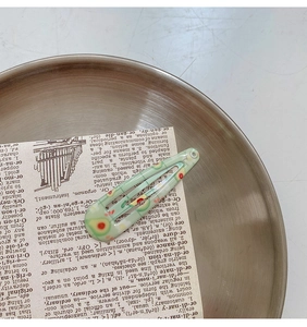 Detailed macro view of light green avocado pattern snap hair clip on a vintage background