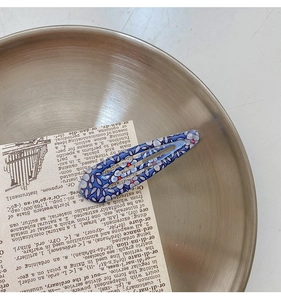 Detail of blue floral print BB hair clip on a silver tray with minimalist backdrop