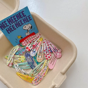 Colorful macaron hair clips with floral and fruit patterns in a pulp tray